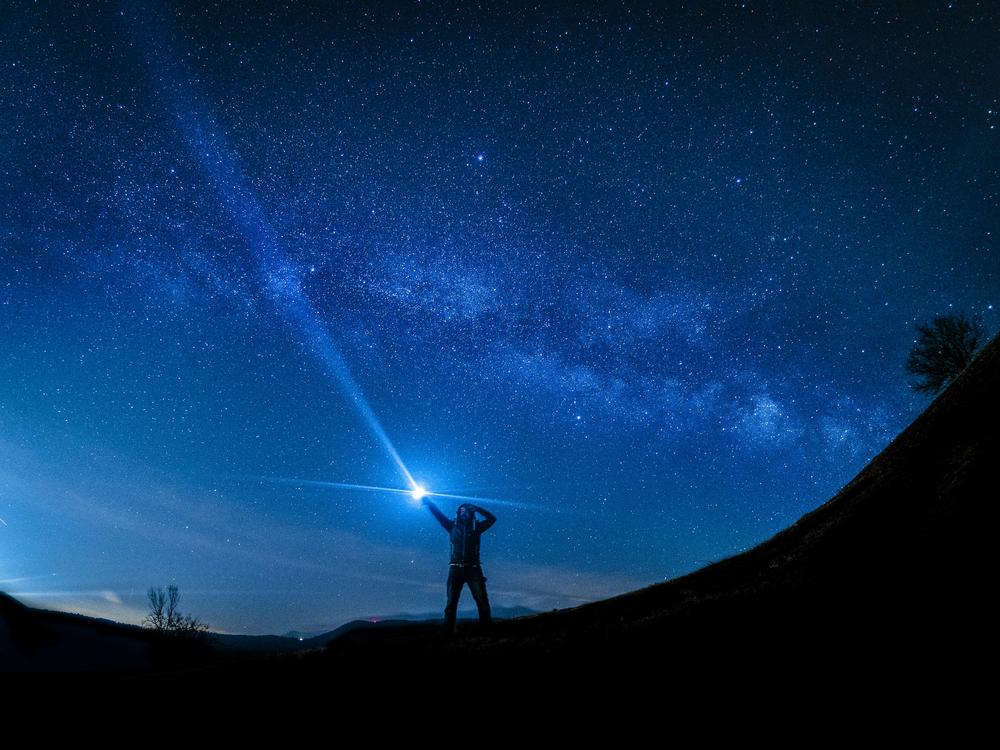 Hombre sosteniendo una fuente de luz en un entorno oscuro, iluminando su rostro y creando un ambiente misterioso.