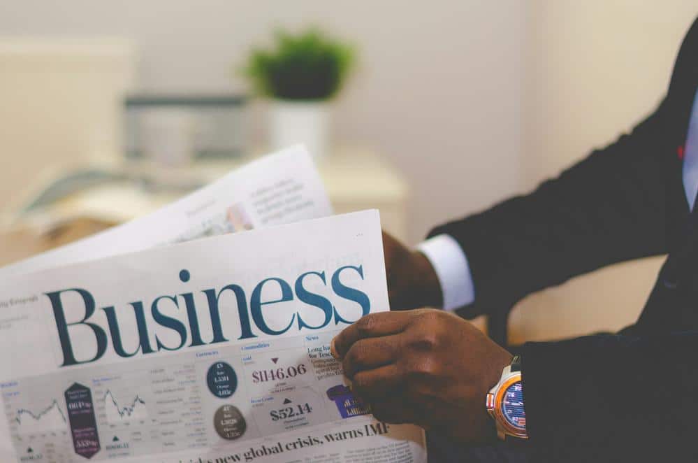 Hombre con traje sosteniendo un periódico empresarial en un entorno profesional.