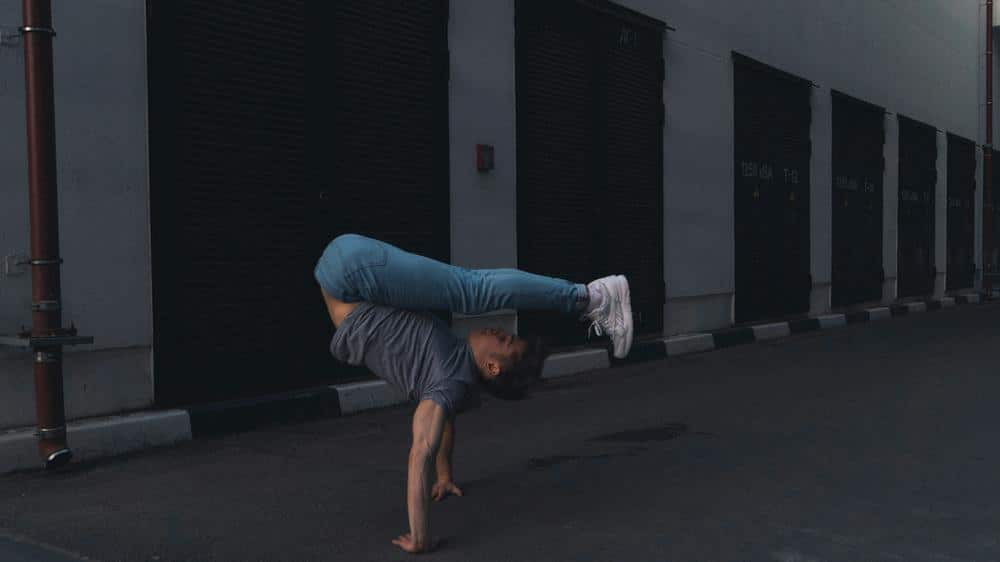 Hombre en un entorno dinámico, mostrando destreza y equilibrio en una postura desafiante. Fondo que sugiere actividad y movimiento. Atuendo que resalta su energía y concentración.